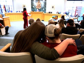 Observers in the gallery hug as former Leduc firefighter Christa Steele speaks to Leduc City Council, Monday April 11, 2022. Steele is one of the named plaintiffs in a class-action lawsuit that alleges women who work at the Leduc Fire Department are subject to a “well-known” culture of sexual harassment and assault, and attempts to report misconduct are met with retaliation.  David Bloom/Post Media