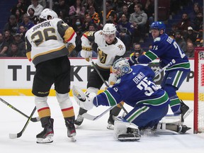Vancouver Canucks goalie Thatcher Demko (35) makes the save as Vegas Golden Knights' Jake Leschyshyn (15) and Mattias Janmark (26) watch during the first period of an NHL hockey game in Vancouver, on Tuesday, April 12, 2022.