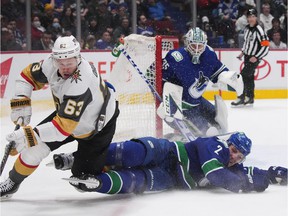 Vegas Golden Knights' Evgenii Dadonov (63) and Vancouver Canucks' Luke Schenn (2) collide in front of goalie Thatcher Demko during the second period of an NHL hockey game in Vancouver, on Tuesday, April 12, 2022.