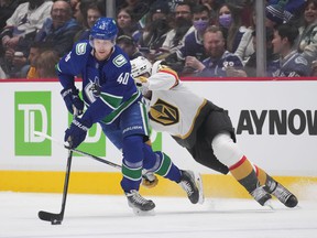 Vancouver Canucks' Elias Pettersson skates with the puck away from Vegas Golden Knights' Chandler Stephenson, back, during the first period of an NHL hockey game in Vancouver, on Tuesday, April 12, 2022.