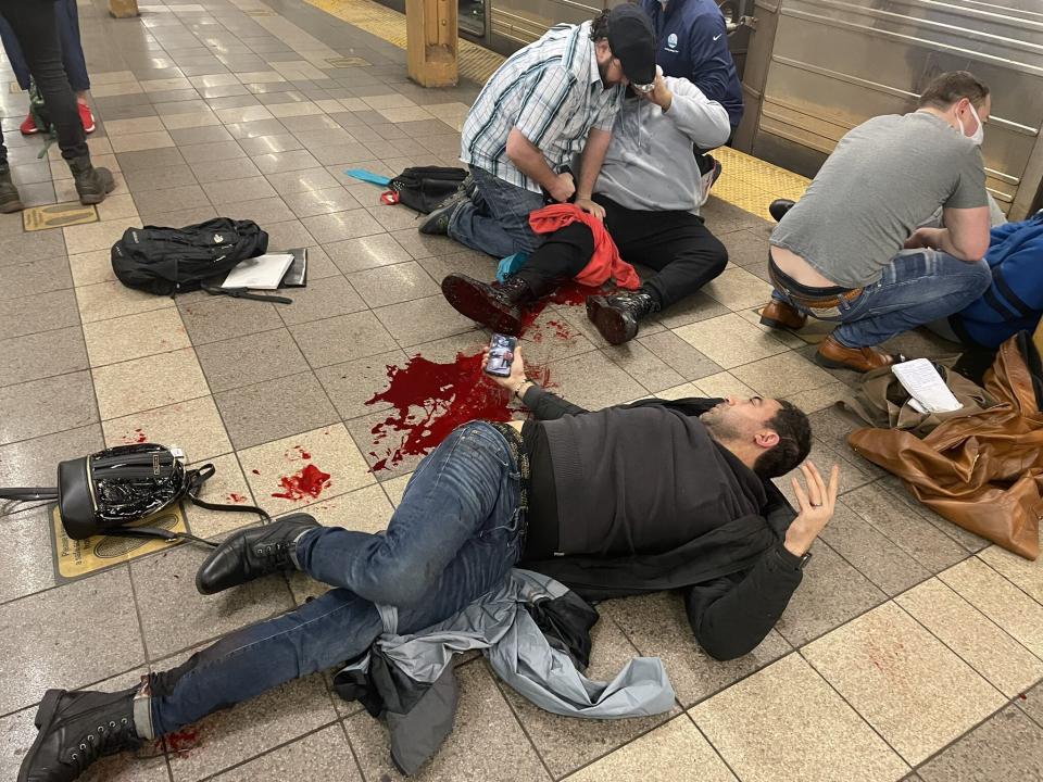 Victims of the shooting on the platform of the subway station, attended by others, with a pool of blood on the floor.