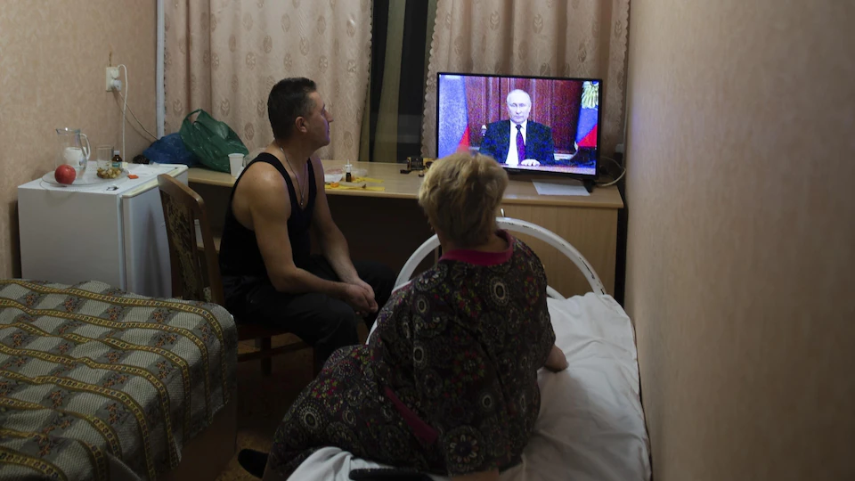 Un homme et une femme regardent Vladimir Poutine à la télévision.