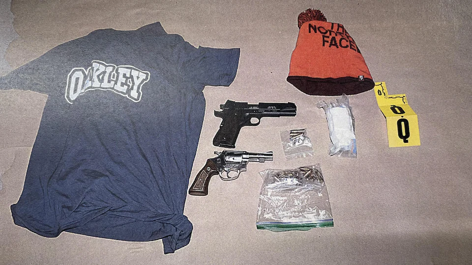 Un t-shirt, une tuque, deux armes de poing, de la poudre blanche et des cartouches de fusil sont étalés sur un papier Kraft.