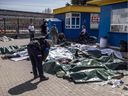 A police officer bends over bodies laid on the ground after a rocket attack killed at least 50 people on April 8, 2022 at a train station in Kramatorsk, Ukraine, that was being used for civilian evacuations.