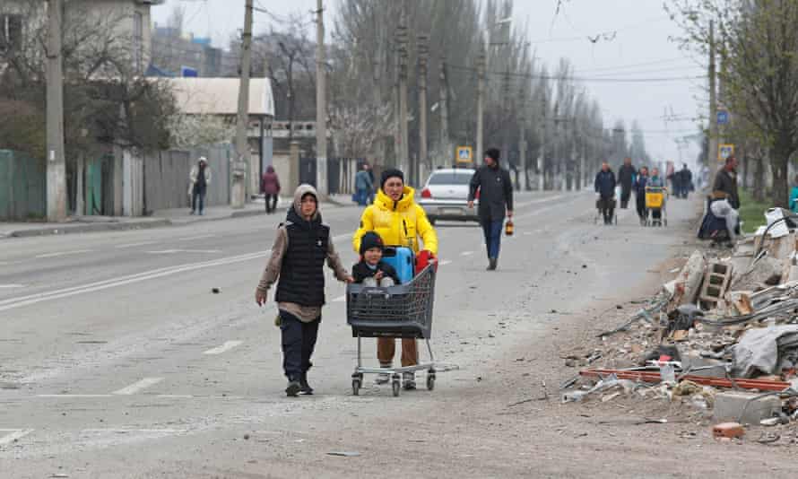 Local residents walk along a street damaged in the southern port city of Mariupol, Ukraine.