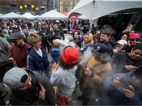 A vendor carries a smoking leaf blower through the crowd after burning marijuana in it and sending smoke out over the crowd during the 4-20 marijuana celebration, in Vancouver, on Wednesday, April 20, 2022.