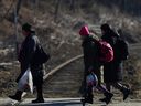 Ukrainian refugees fleeing Russia's invasion of Ukraine, walk after crossing the border between Ukraine and Poland, in Kroscienko, Poland, Tuesday, March 22, 2022.