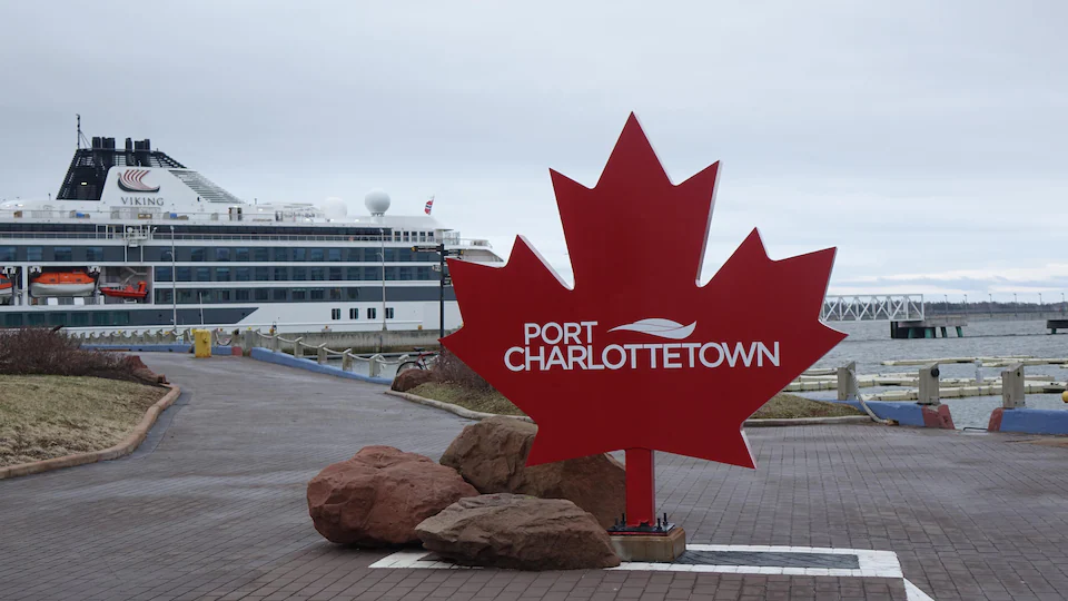 Un panneau contenant l'inscription Port Charlottetown. Un bateau de croisière se trouve au fond de l'image. 