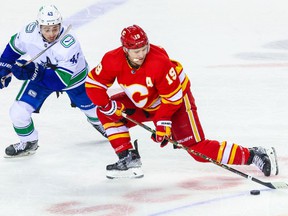 Apr 23, 2022;  Calgary, Alberta, CAN;  Calgary Flames left wing Matthew Tkachuk (19) and Vancouver Canucks defenseman Quinn Hughes (43) battle for the puck during the first period at Scotiabank Saddledome.