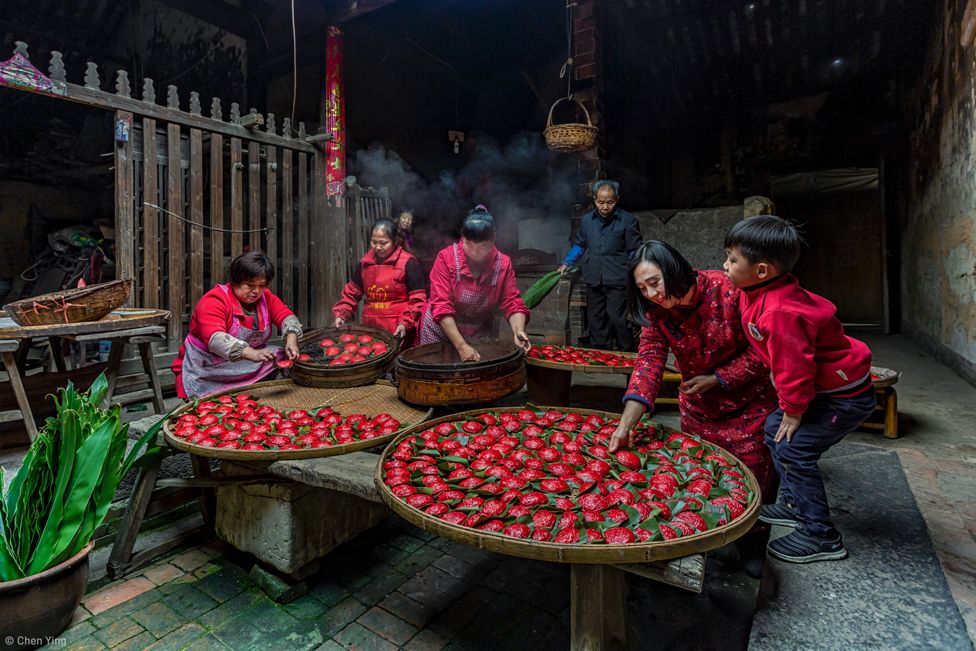 A family making red colored dumplings