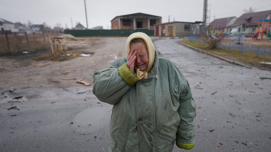 A woman cries in front of houses damaged by a Russian airstrike