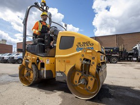 Jonah Simmons with the City of Edmonton rolls fresh asphalt to repair a pothole on Thursday, April 28, 2022.