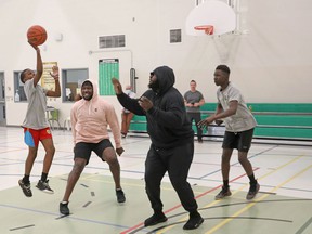 Jesse Luketa (pink sweater) plays some basketball at his old high school, St Pat's in Ottawa with his friend Neville Gallimore (black sweater) while current student Caprice Masudi of Grade 7 makes the shot, April 29, 2022.