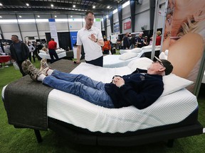 Frank Wirag tries out an adjustable bed while sales representative James McIntosh from Sleep Country provides details at the 38th annual Windsor Home and Garden Show at the Central Park Athletics on Friday, April 29, 2022.