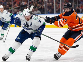 Brett Kulak #27 of the Edmonton Oilers high sticks JT Miller #9 of the Vancouver Canucks during the first period at Rogers Place on April 29, 2022 in Edmonton, Canada.