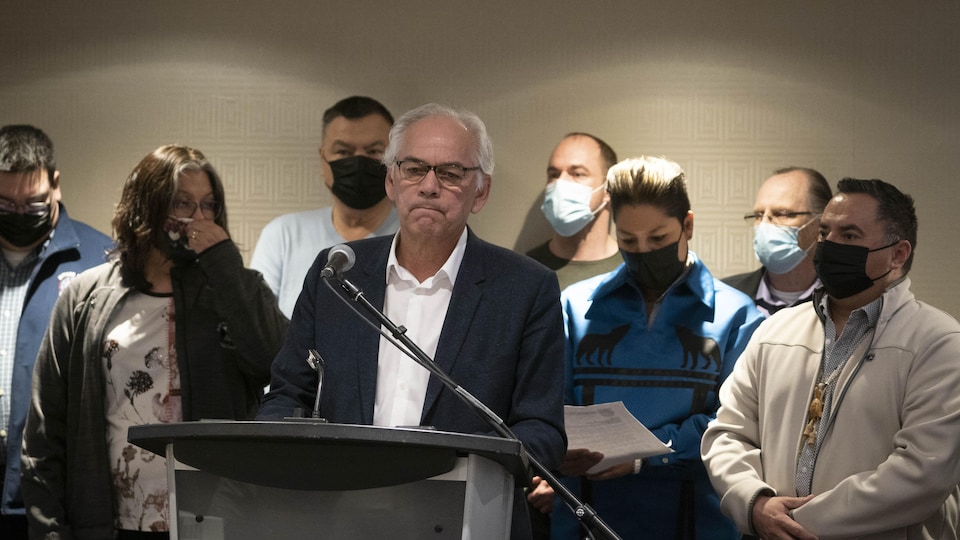 Ghislain Picard speaks at the microphone in front of the lectern along with other First Nations members.