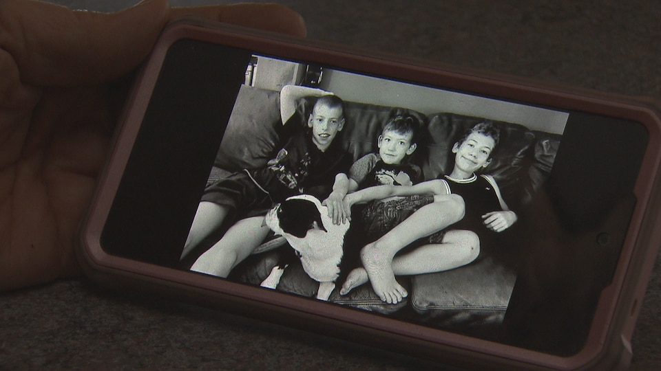 A cell phone with a picture of three children. 
