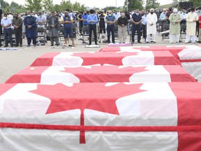 Mourners pray as caskets draped in Canadian flags are lined up at a funeral for the four Muslim family members killed in a deadly vehicle attack, at the Islamic Center of Southwest Ontario in London, Ont., on Saturday, June 12, 2021. Talat Afzaal , 74, her son Salman Afzaal, 46, his wife Madiha Salman, 44, and their 15-year-old daughter Yumna Salman all died last Sunday night while out for a walk after a man in a truck drove them down in what police have called a premeditated attack because they were Muslim.