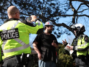Truck driver Brian Baekgaard talks with Victoria Police after receiving a ticket for honking his horn while he joins hundreds of convoy supporters gathered at the BC Legislature to protest COVID-19 mandates in the province while in Victoria, BC, on Saturday, March 5, 2022 .