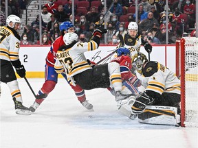 Mathieu Perreault #85 of the Montreal Canadiens takes down Charlie McAvoy #73 of the Boston Bruins near goaltender Jeremy Swayman #1 during the second period at Center Bell on April 24, 2022 in Montreal.