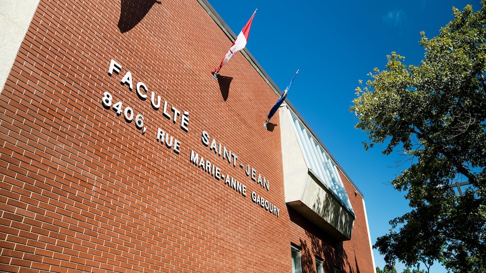 Close-up of the side of the building on a sunny summer day.  We can read Faculté Saint-Jean, 8496 rue Marie-Anne Gaboury.