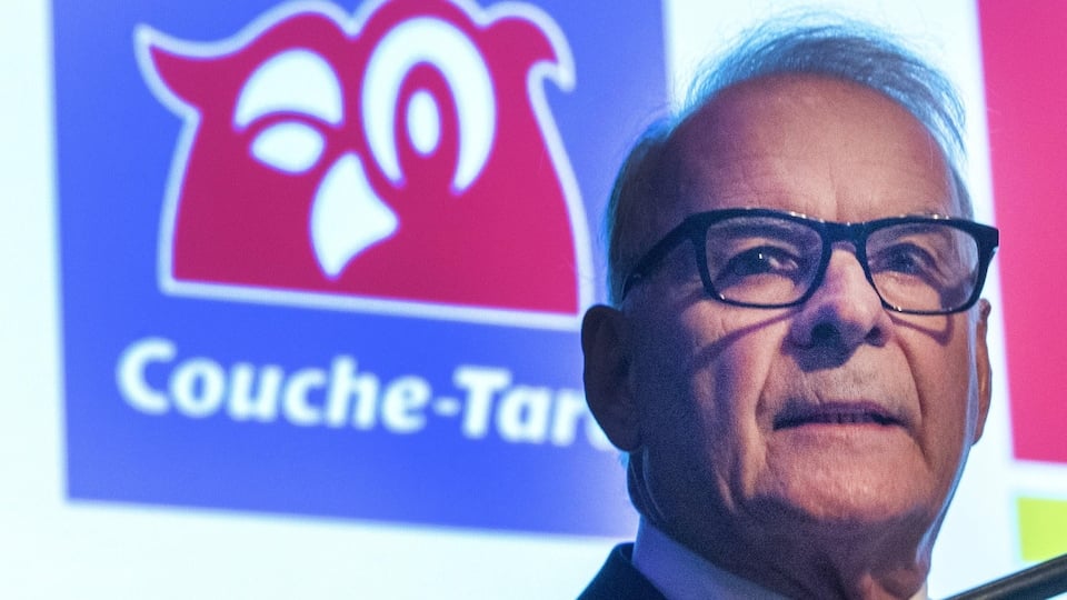 Alain Bouchard in front of a projection of the Couche-Tard logo.