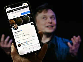 In this photo illustration, a phone screen displays the Twitter account of Elon Musk with a photo of him shown in the background, on April 14, 2022, in Washington, DC