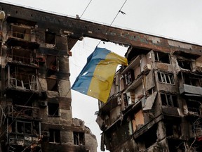 A view shows a torn flag of Ukraine hung on a wire in front of an apartment building destroyed during Ukraine-Russia conflict in the southern port city of Mariupol, Ukraine Thursday, April 14, 2022.