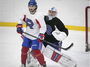 Laval Rocket goalie Cayden Primeau looks over the shoulder of Justin Ducharme during practice on Monday, Feb. 14, 2022.