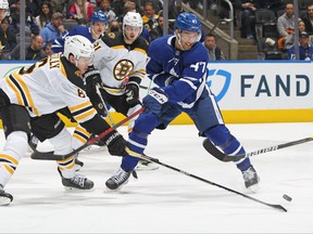 Bruins' Mike Reilly (left) battles against Maple Leafs' Pierre Engvall at Scotiabank Arena last night.