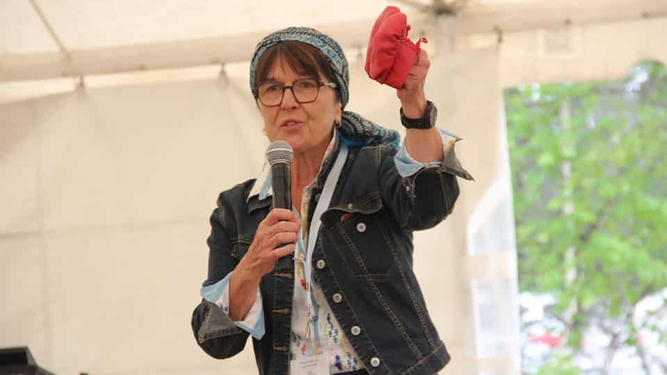 Anne Panasuk holds red child's moccasins.