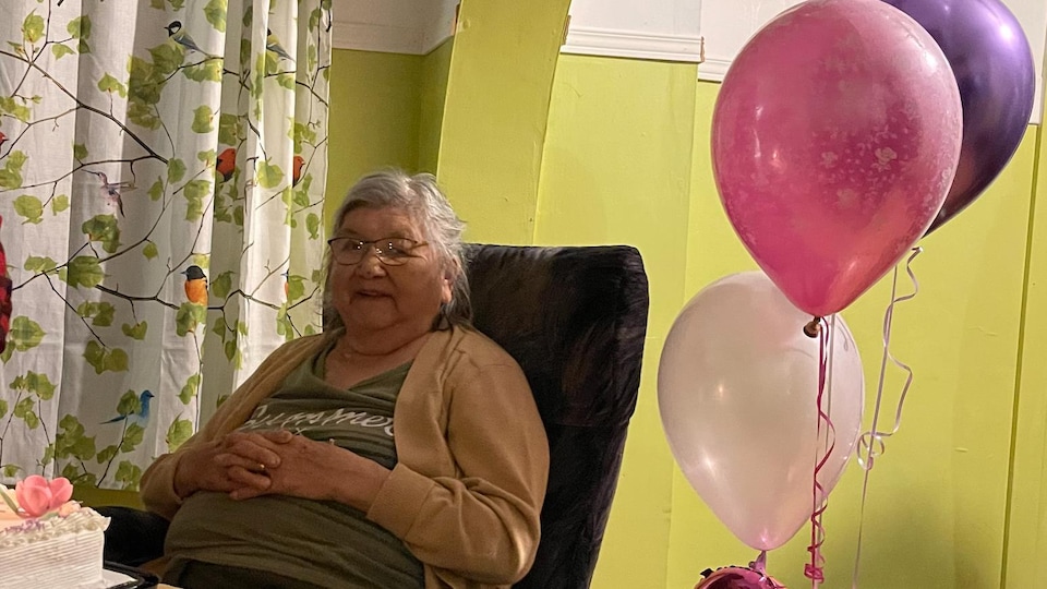 An old lady with birthday balloons and the number 81