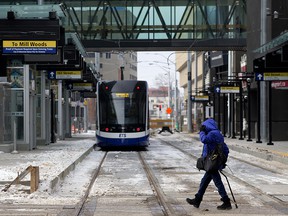 A pedestrian makes their way past a light rail transit (LRT) car parked at the under construction 102 Street LRT stop in downtown Edmonton, on Tuesday, March 1, 2022.