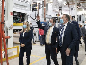 Premier François Legault, right, visits the Prévost bus plant with its president François Tremblay, centre, in Ste-Claire.