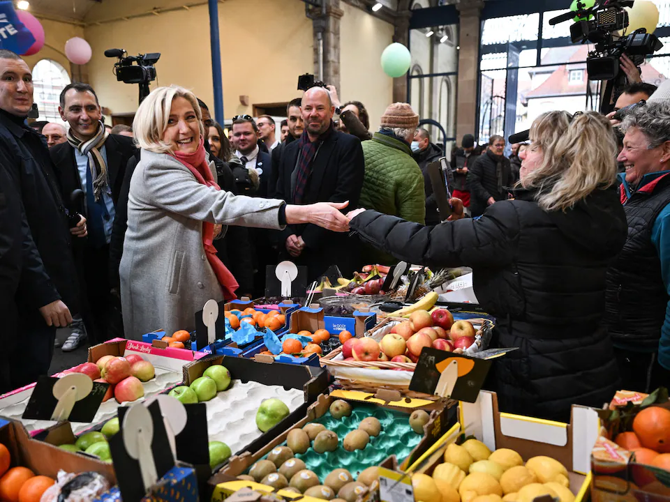 Marine Le Pen, devant un étal, serre la main à une marchande.