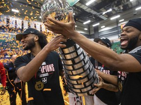 Carleton Ravens' Biniam Ghebrekidan (left) and Lloyd Pandi hoist the trophy after defeating the Saskatchewan Huskies' during the gold medal U Sports Men's Final 8 Basketball Championship, in Edmonton Sunday.  The win marks the third championship in a row and the 16th over 19 years.  Jason Franson/THE CANADIAN PRESS