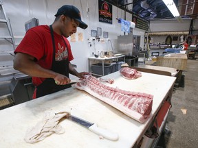 Hashit Haneem, a butcher at SK Quality Meats, cuts up porkloin and loads in into the display case at St. Lawrence Market on Wednesday, April 20, 2022.