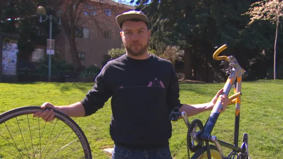 Un homme tient dans ses mains des morceaux de vélo.