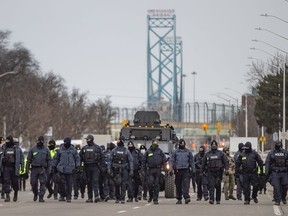 A large line of police officers march south on Huron Church Road on Saturday, Feb. 13, 2022, clearing protesters who have blocked the road since Monday.