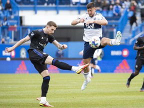 CF Montreal's Joel Waterman, left, clears the ball as Vancouver Whitecaps' Lucas Cavallini moves in during second half MLS soccer action in Montreal, Saturday, April 16, 2022.