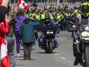 A man stands in salute as a wave of motorcycles passes during the 'Rolling Thunder' convoy on Elgin St. between Albert St. and Laurier St. on Saturday.