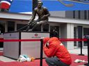A man takes a moment and kneels at the foot of the Guy Lafleur statue in Montreal to pay his respects to Lafleur, who passed away on April 22, 2022.