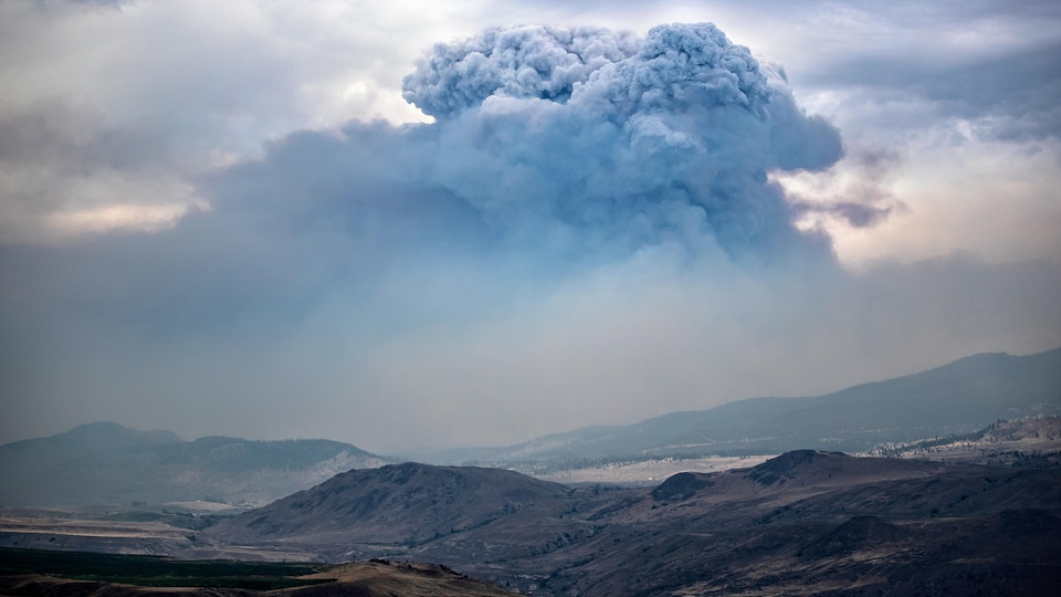 A huge cloud caused by smoke from forest fires above valleys.