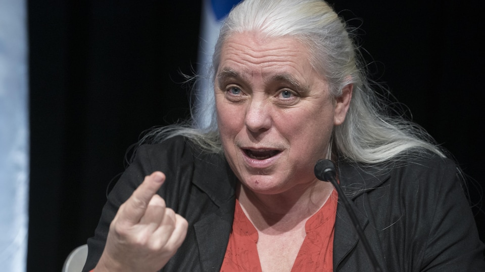 Manon Massé in a press briefing raises her index finger. 