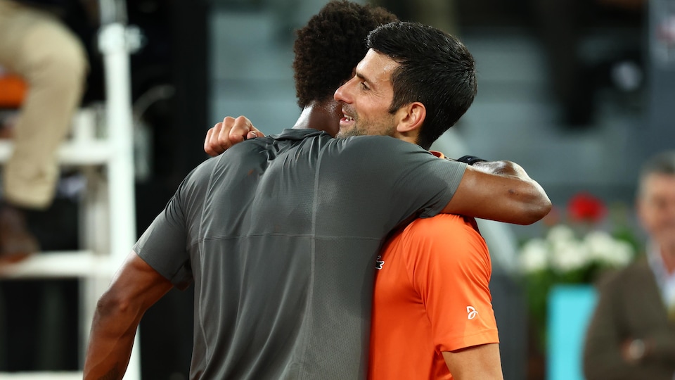 Two tennis players hug each other at the end of a match.