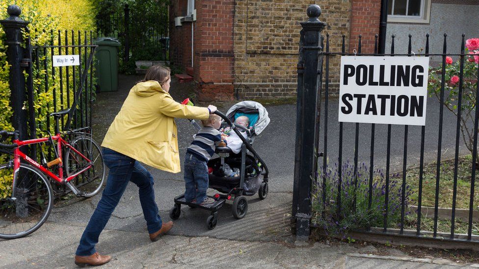 Woman pushes pram and child into polling station