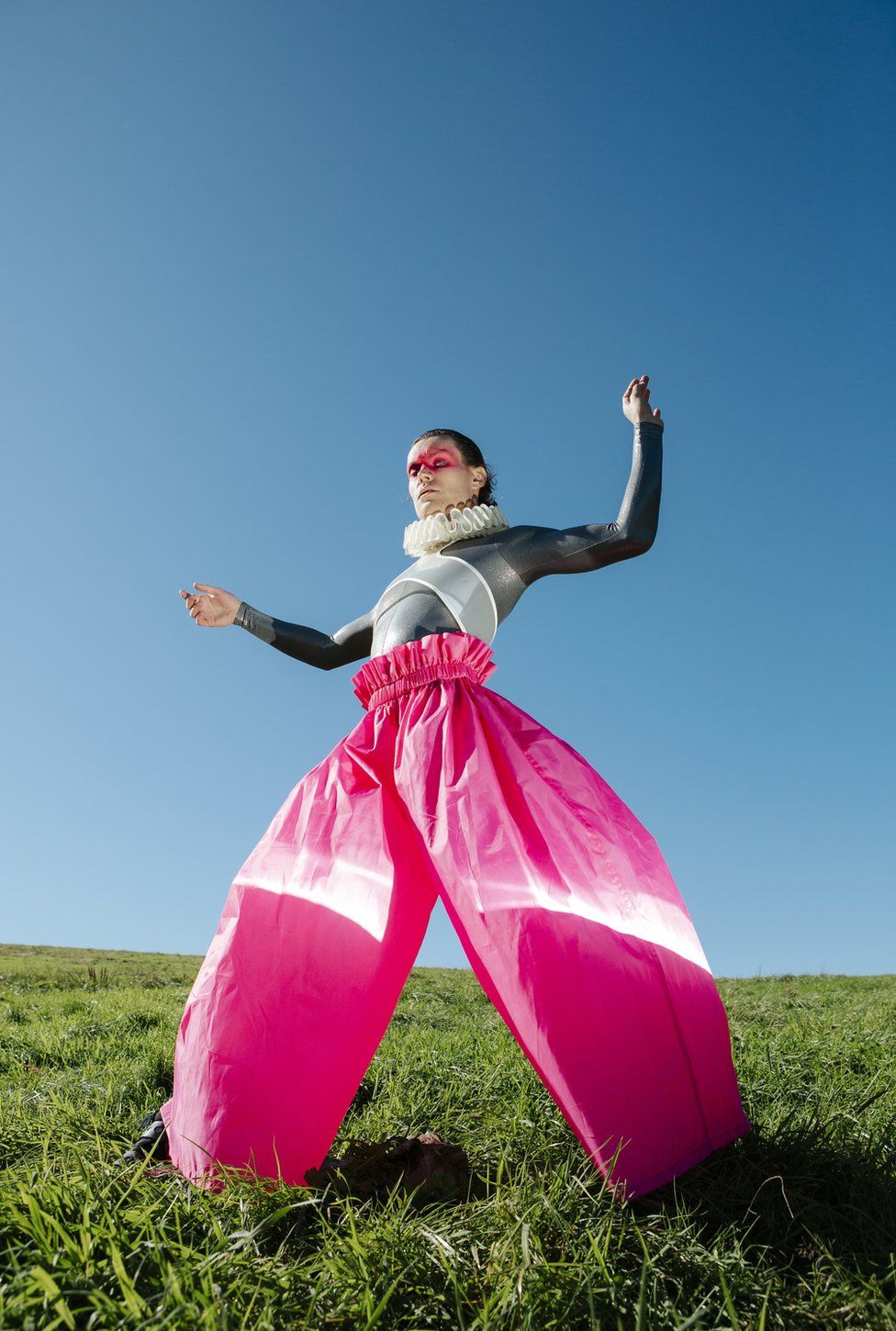 A fashion model poses with large pink trousers