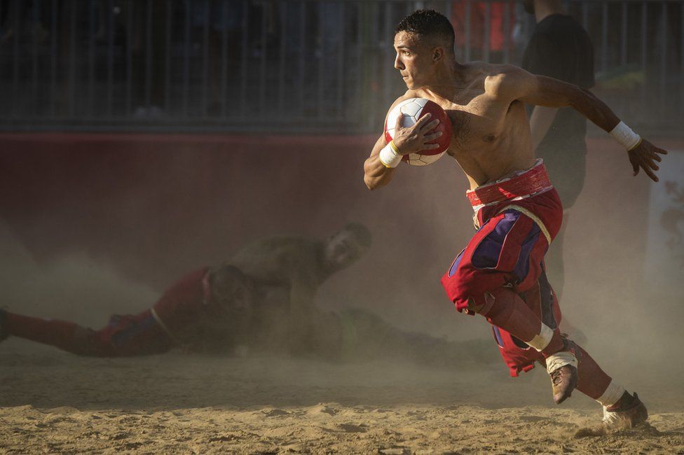 A player runs with a ball whilst playing Calcio Storico in Florence, Italy