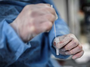 A health-care worker handles a sample collected from a patient tested for COVID-19.