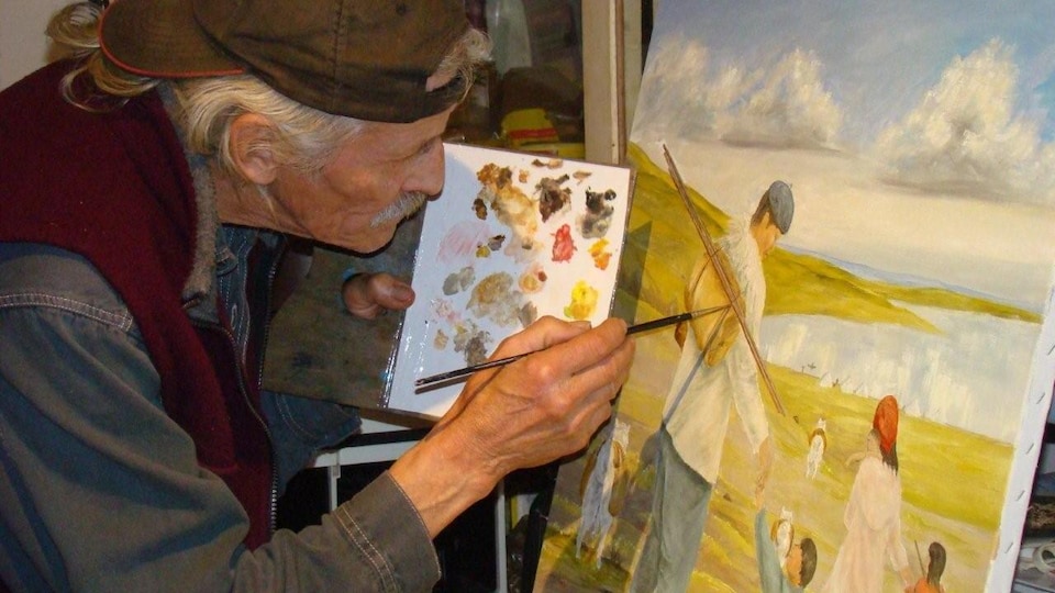 A man paints a picture in a workshop.